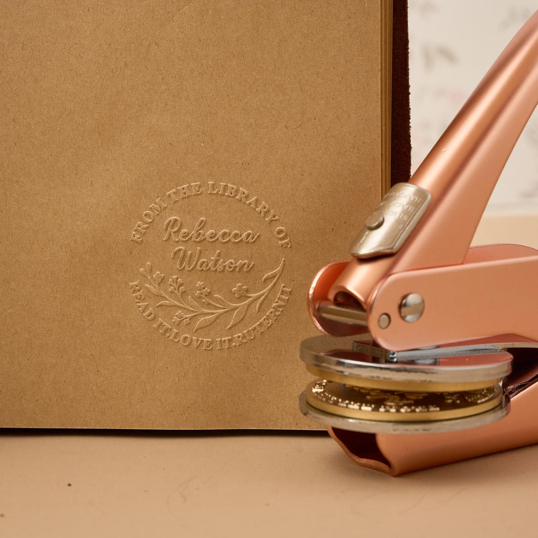 Close-up of a custom embossing stamp tool creating a raised brand logo on luxury paper, used for e-commerce packaging and customer communications
