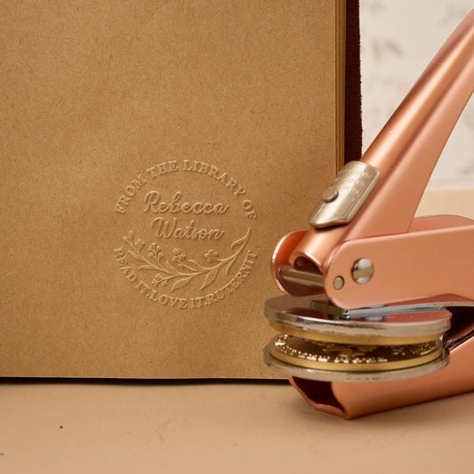 Close-up of a custom embossing stamp tool creating a raised brand logo on luxury paper, used for e-commerce packaging and customer communications